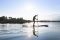 Ein Mann paddelt im Sonnenlicht mit seinem Stand-Up-Paddle über einen See.